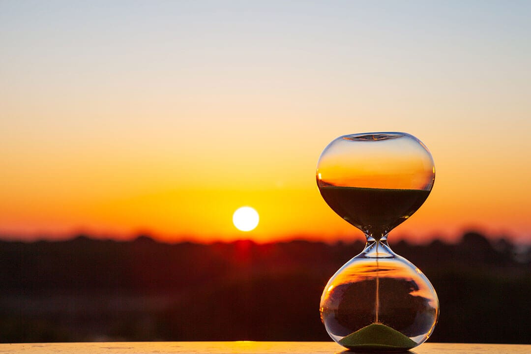 Hourglass reflecting setting sun on windowsill