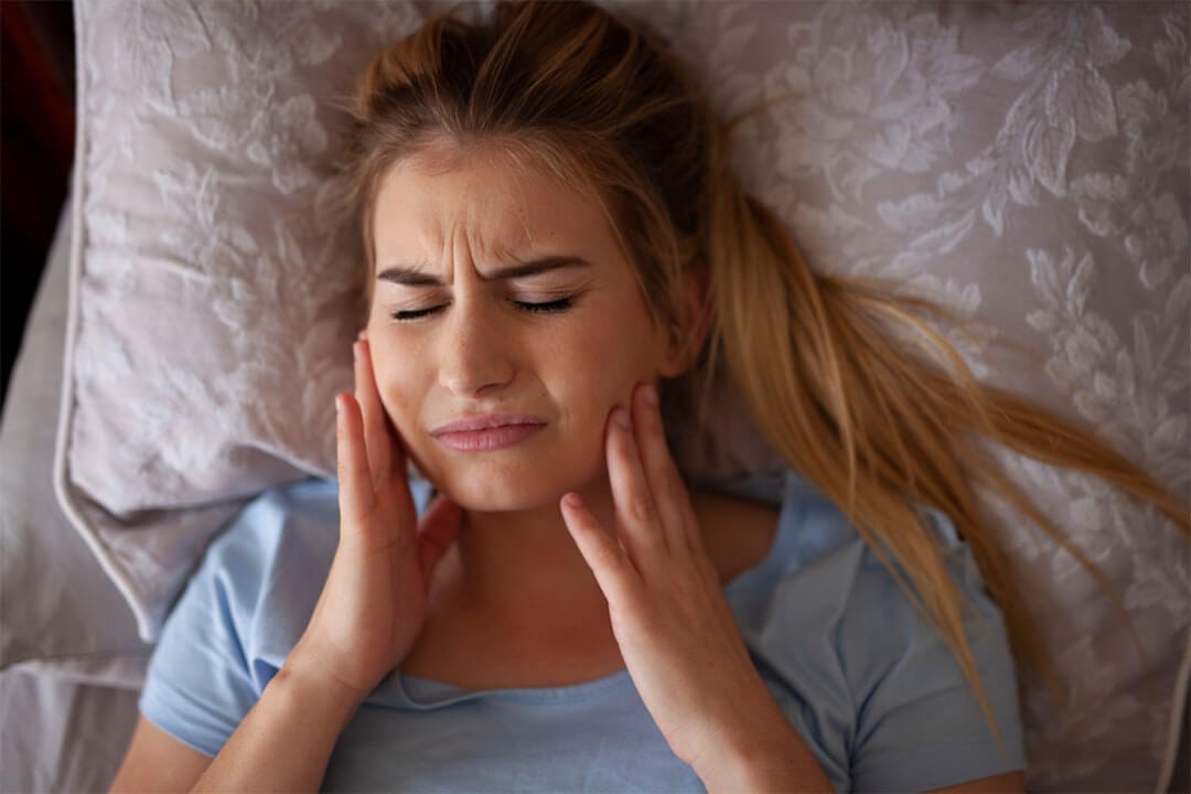 Woman laying in bed with jaw pain