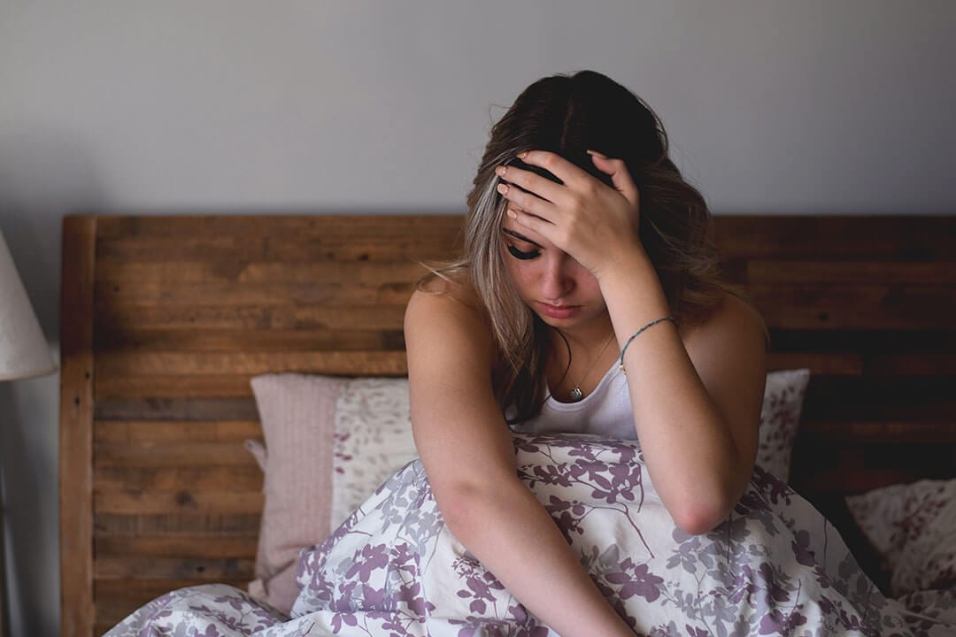 Young woman sitting in bed feeling stressed