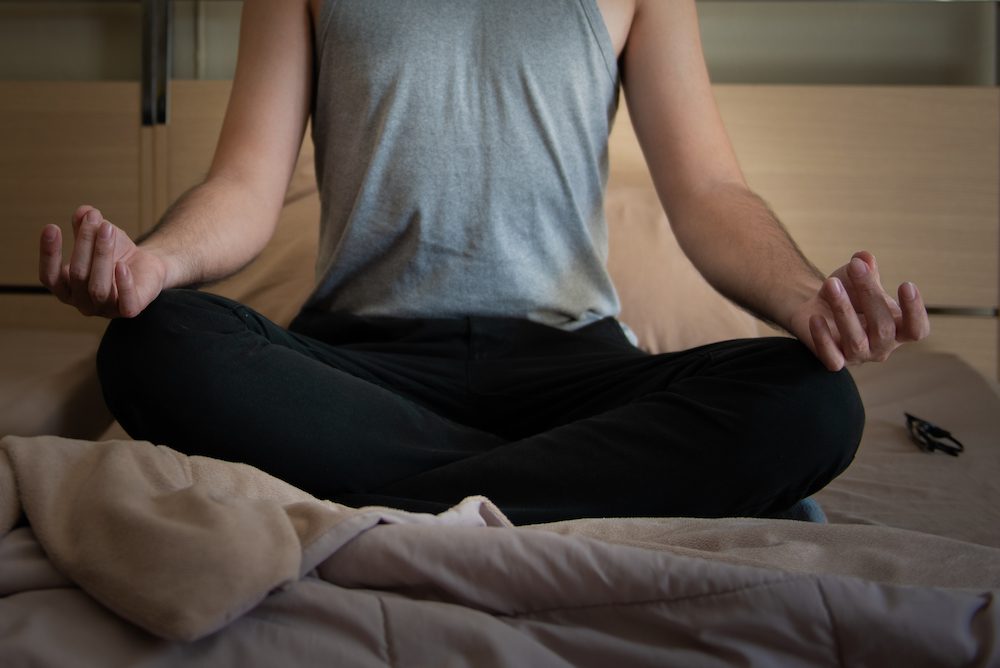 stock photo of a man meditating in bed
