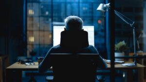 stock photo of a person sitting at a computer at night