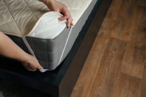 photo of a woman putting a mattress pad on top of a mattress