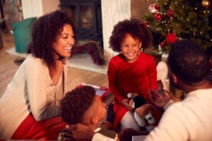 A family joyfully swaps presents while sitting next to a christmas tree