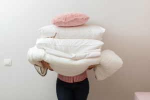 Woman holding a stack of pillows and bedding